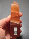 Honey calcite crystal held in a hand with 'Qurizen' branding.