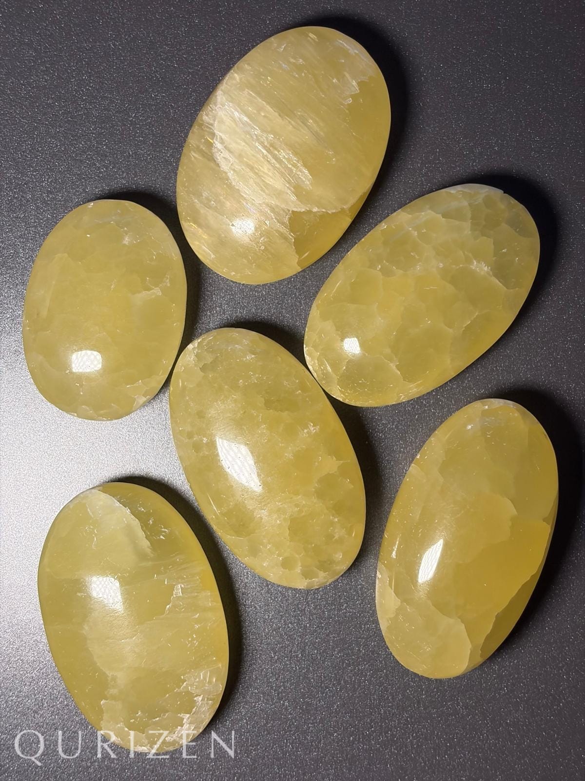 Seven yellow cat's eye gemstones on a dark gray background with 'Qurizen' branding.