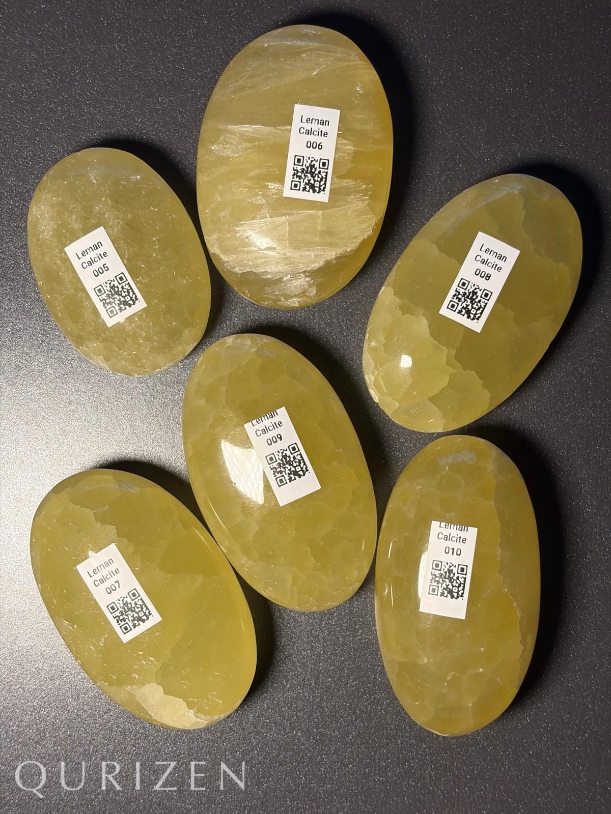 Oval-shaped stones with QR code labels on a dark surface, branded 'Qurizen'.