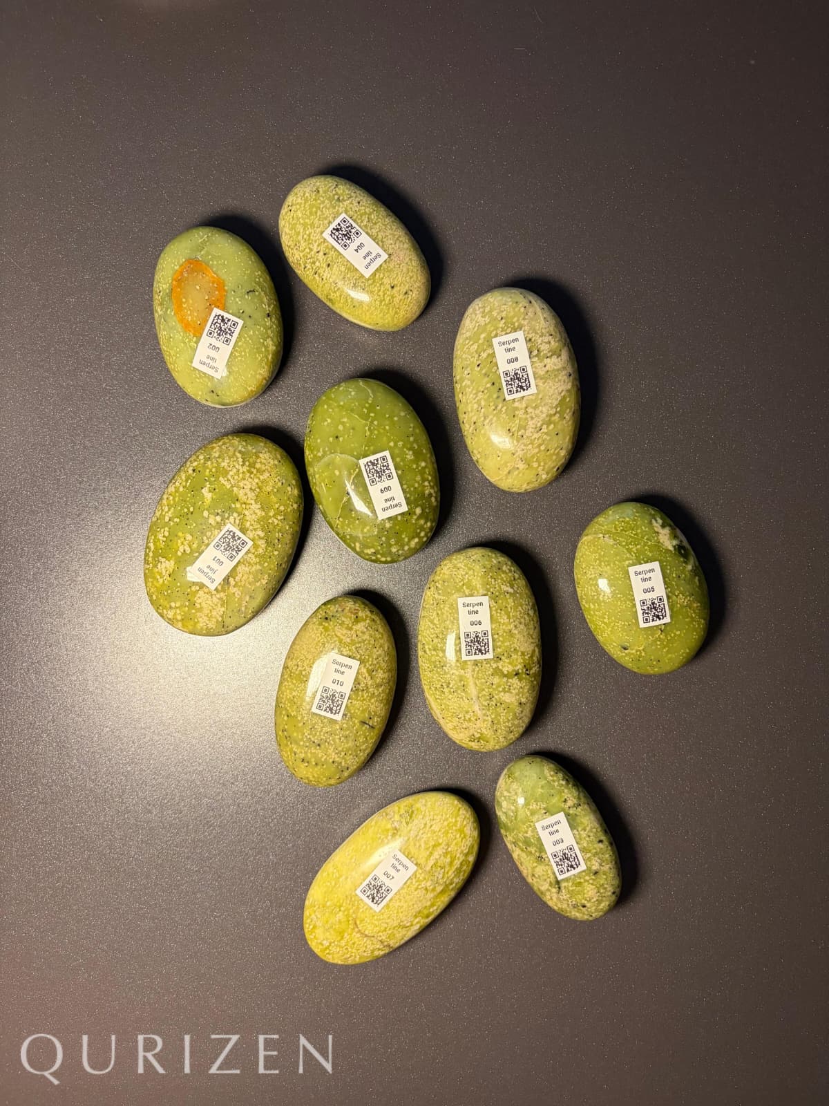 Green stones with QR codes on a dark surface, featuring the brand 'Qurizen'.