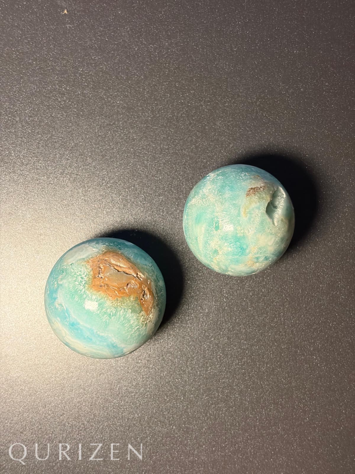 Two Smithsonite stones on a dark surface with 'Qurizen' branding.